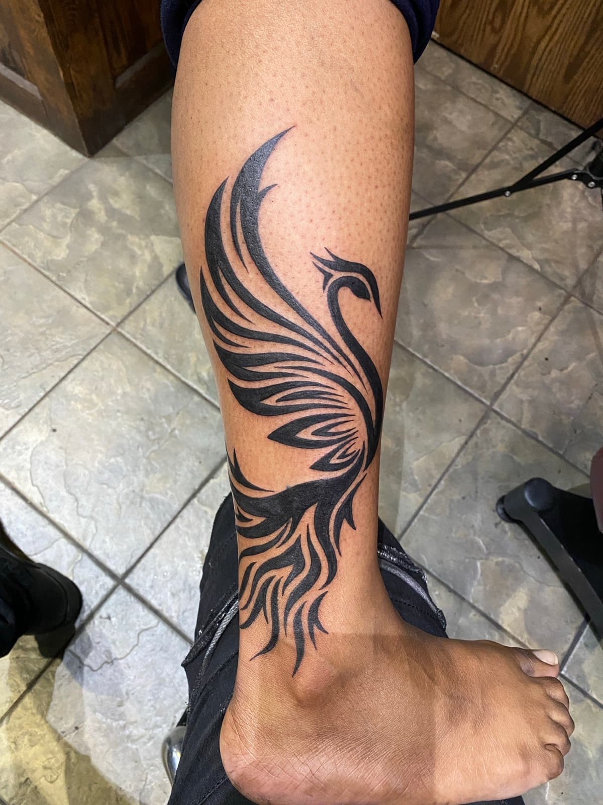 Blackwork tattoo tribal phoenix flowing design on shin and calf in Los Angeles