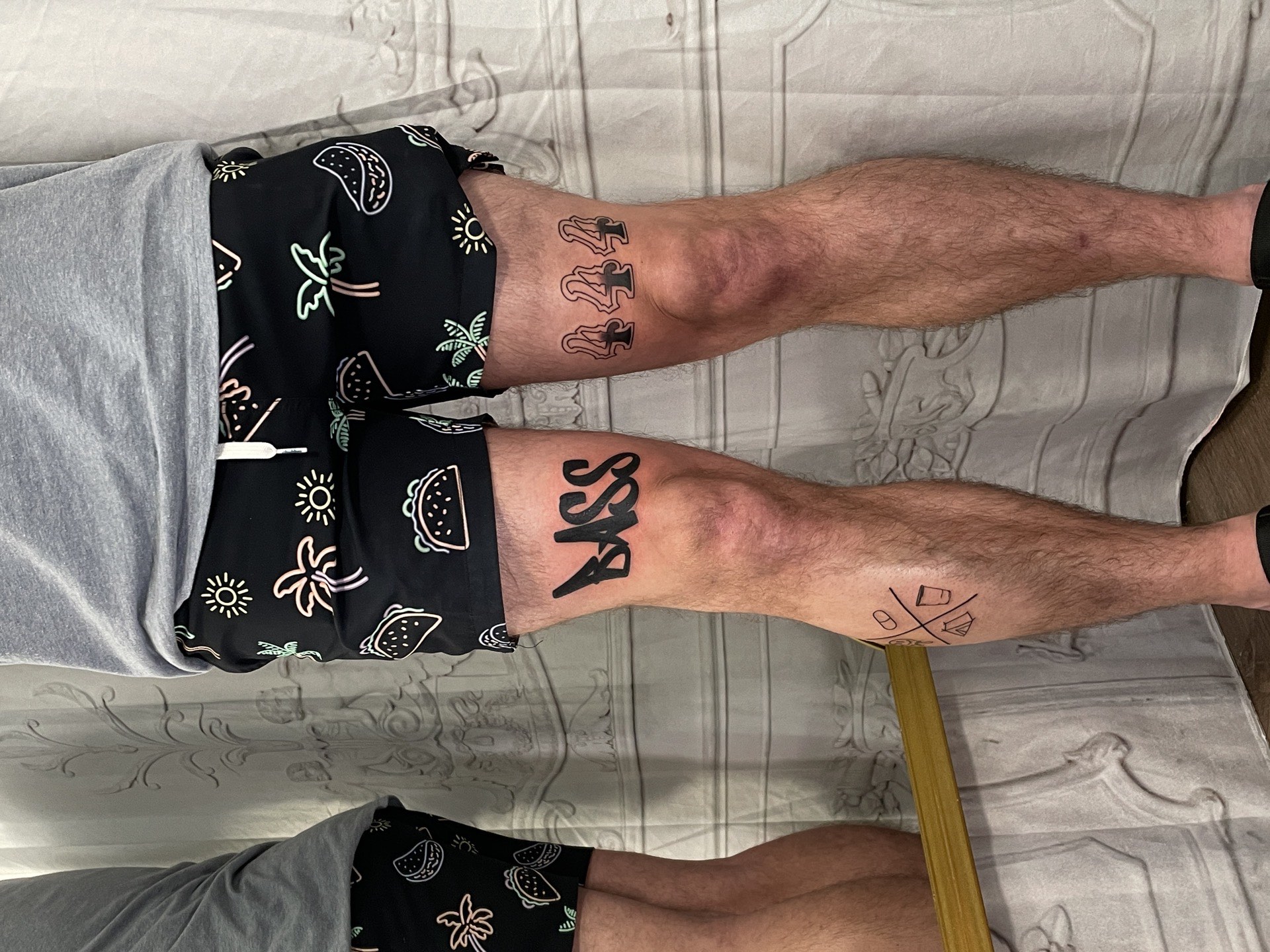 Blackwork tattoo bold BASS lettering on knee in Los Angeles