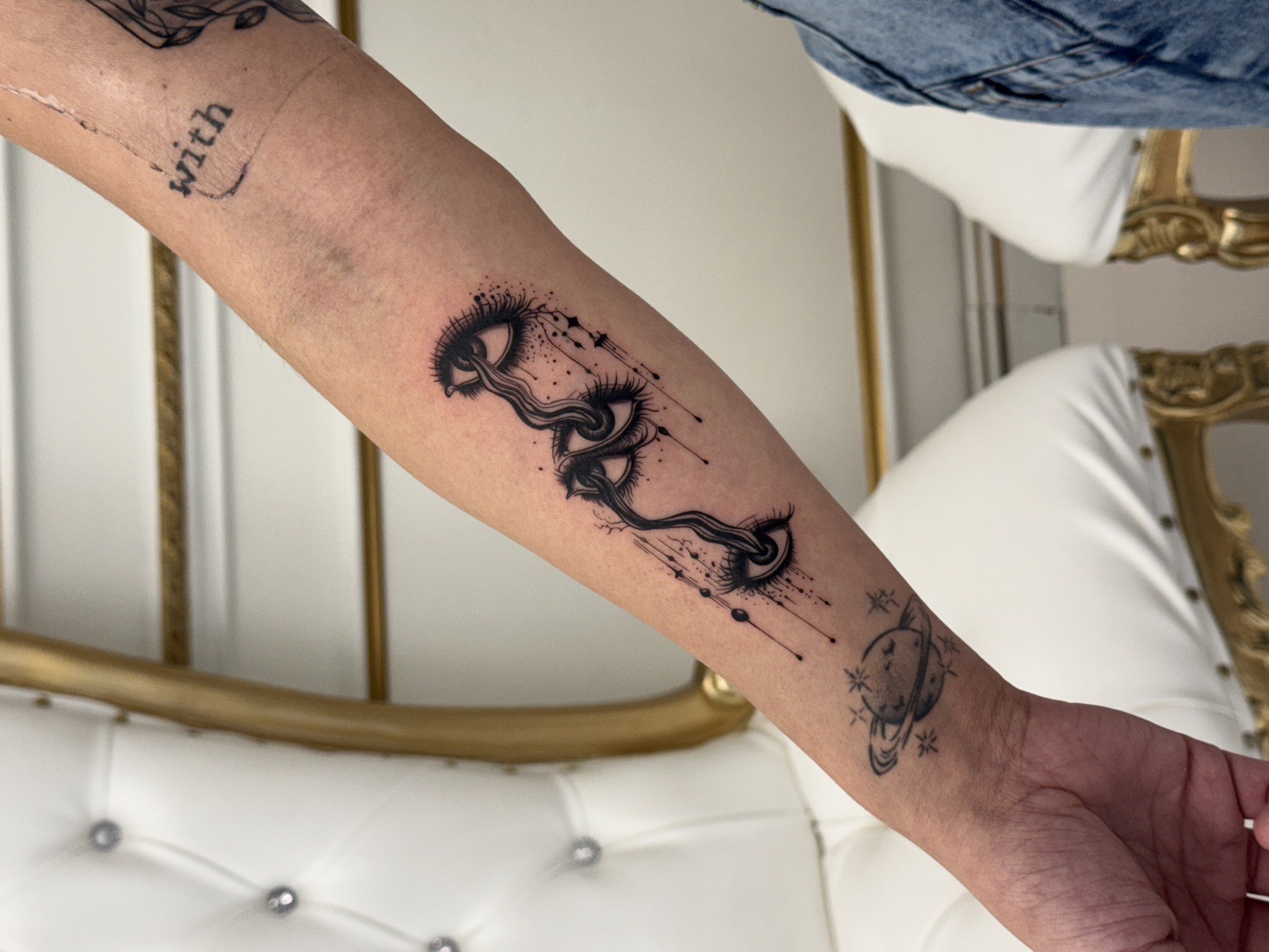 Blackwork tattoo surreal eyes with snakes and celestial planet on forearm in Los Angeles