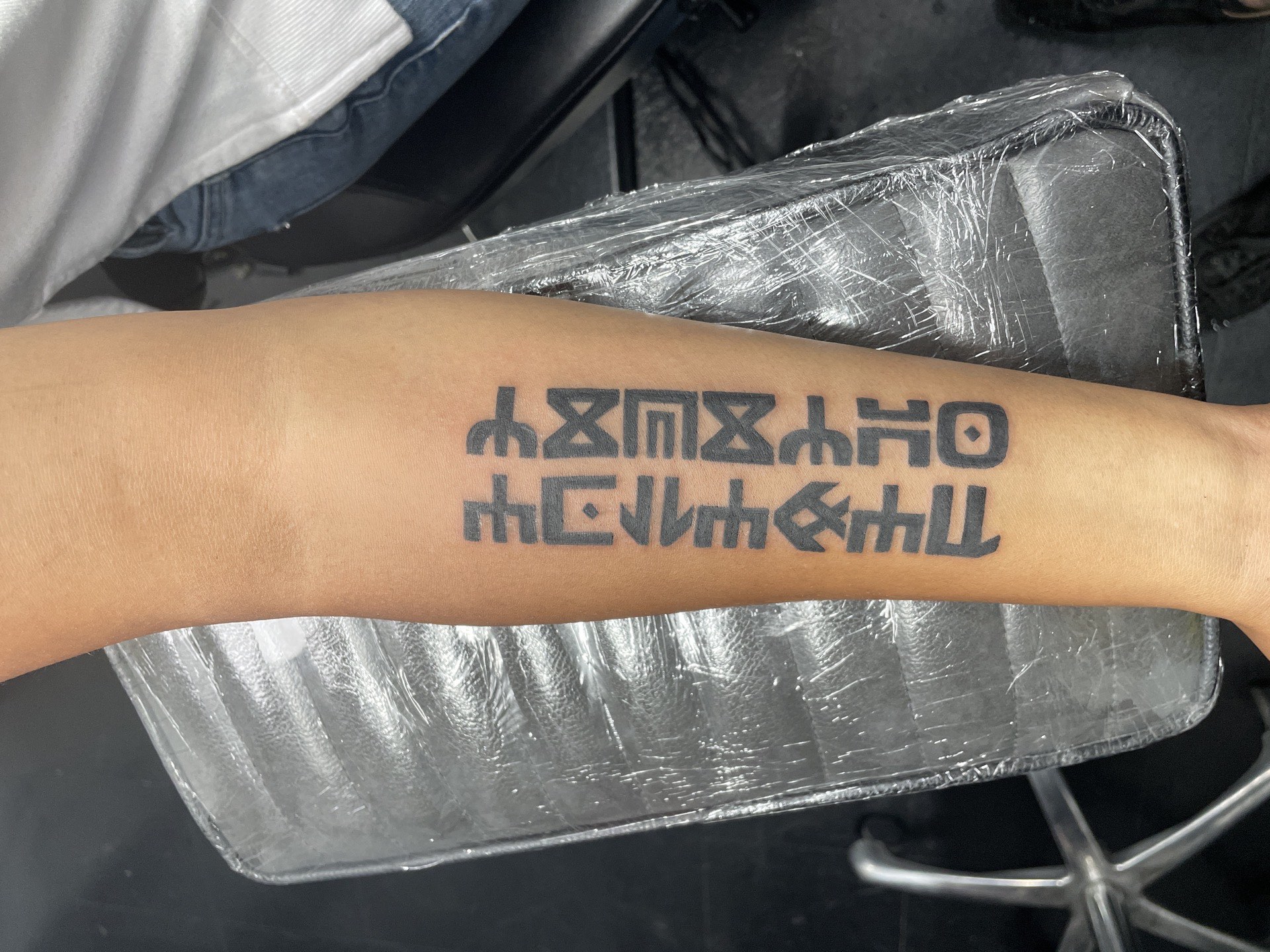 Blackwork tattoo bold Ethiopic script on forearm in Los Angeles