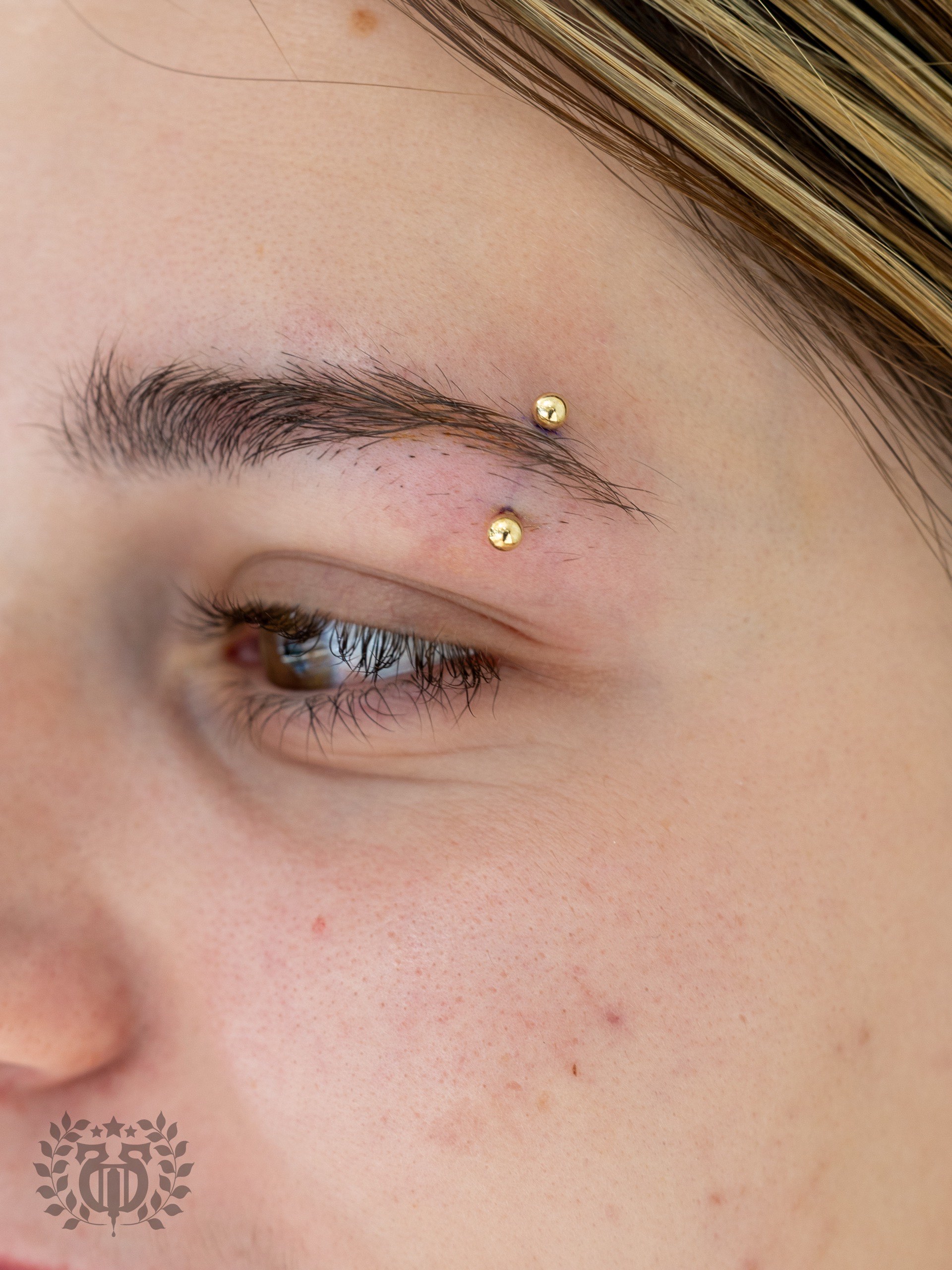 Gold ball curved barbell eyebrow piercing at Apollo Studio Los Angeles