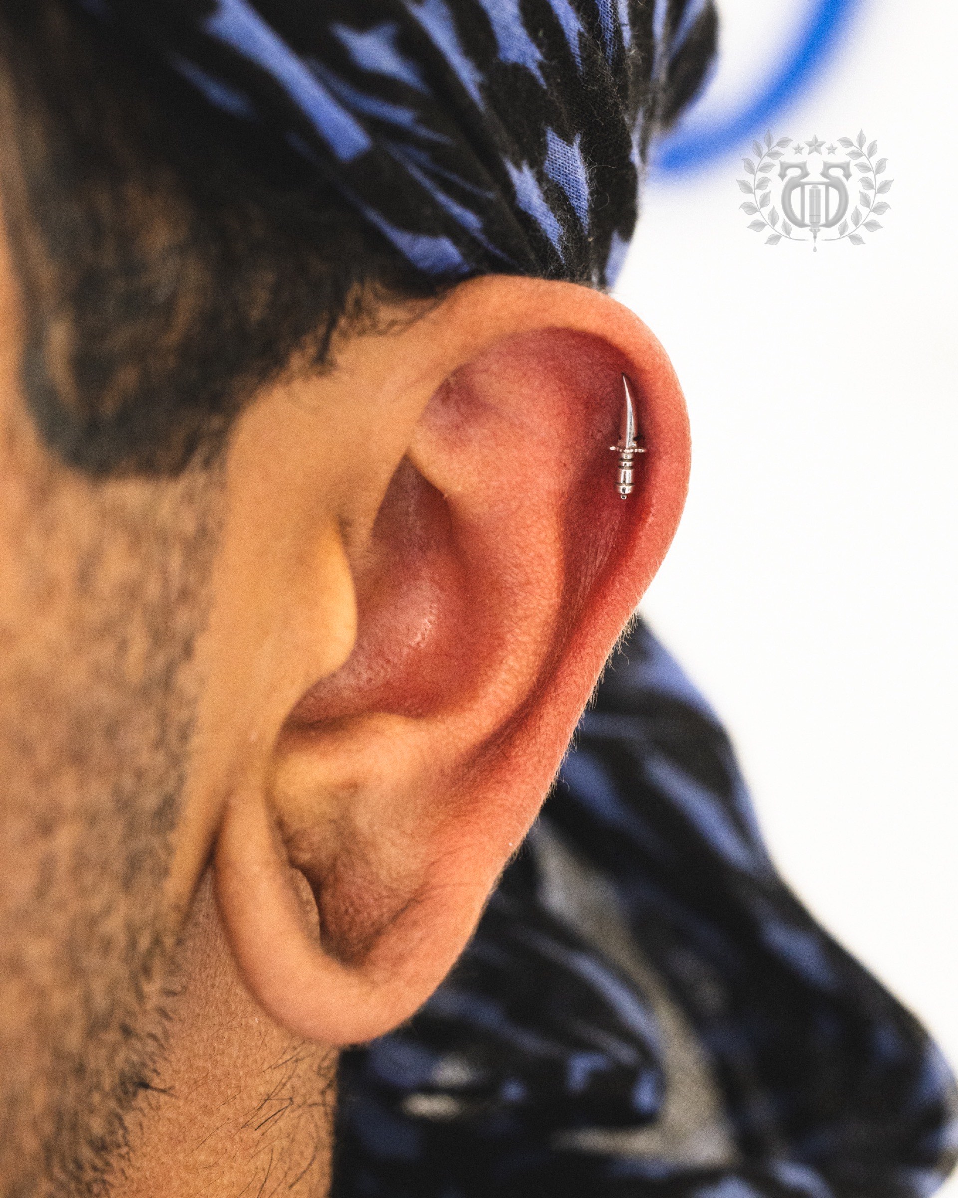 Silver sword dagger hoop cartilage piercing on male client at Apollo Studio Los Angeles
