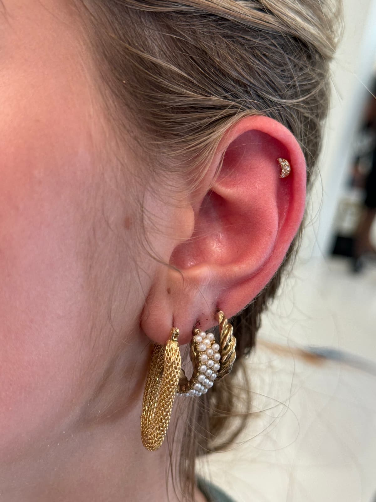 Gold CZ crescent moon cartilage stud with pearl and rope lobe hoops at Apollo Tattoo and Piercing