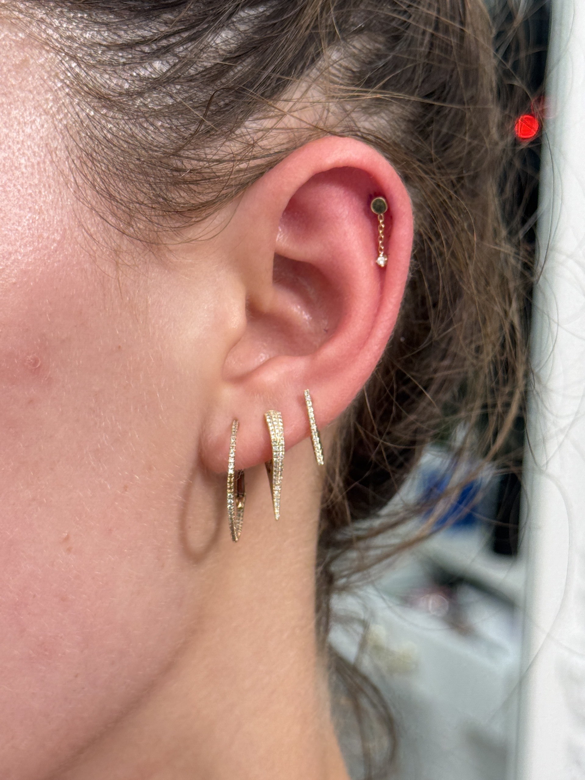 Gold chain dangle cartilage stud with triple gold CZ spike lobe hoops at Apollo Studio LA