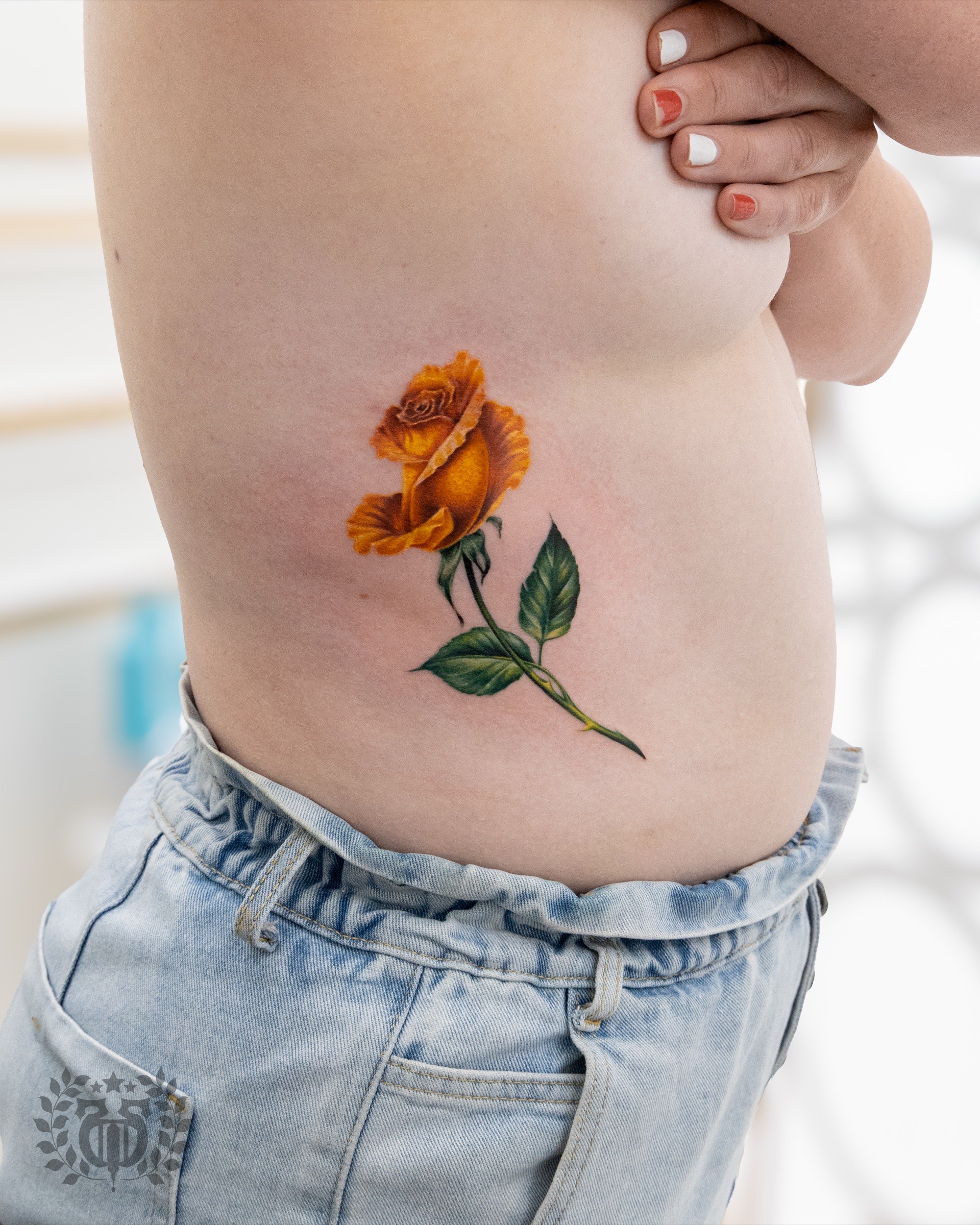 Color realistic yellow orange rose realism tattoo on side torso in Los Angeles