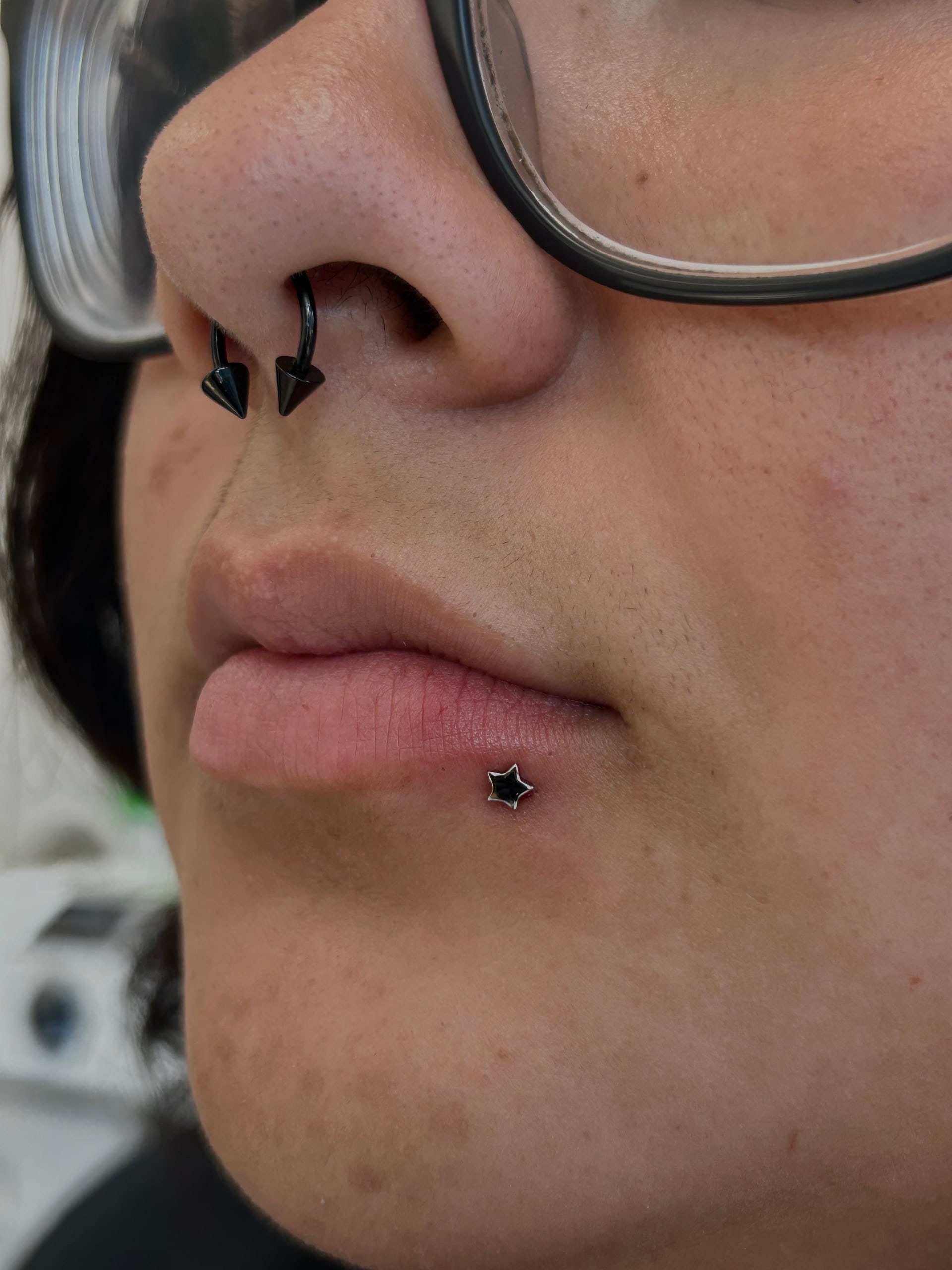 Labret piercing with black star stud and black septum horseshoe at Apollo Tattoo and Piercing