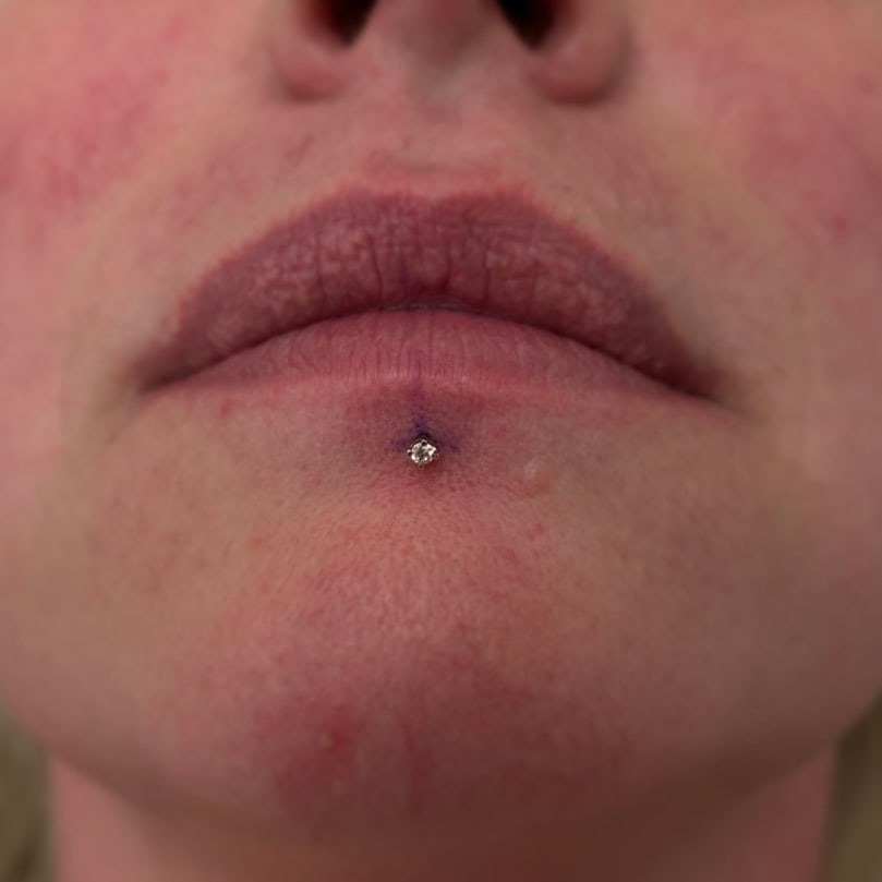 Center labret piercing with silver bezel CZ diamond stud at Apollo Studio Los Angeles