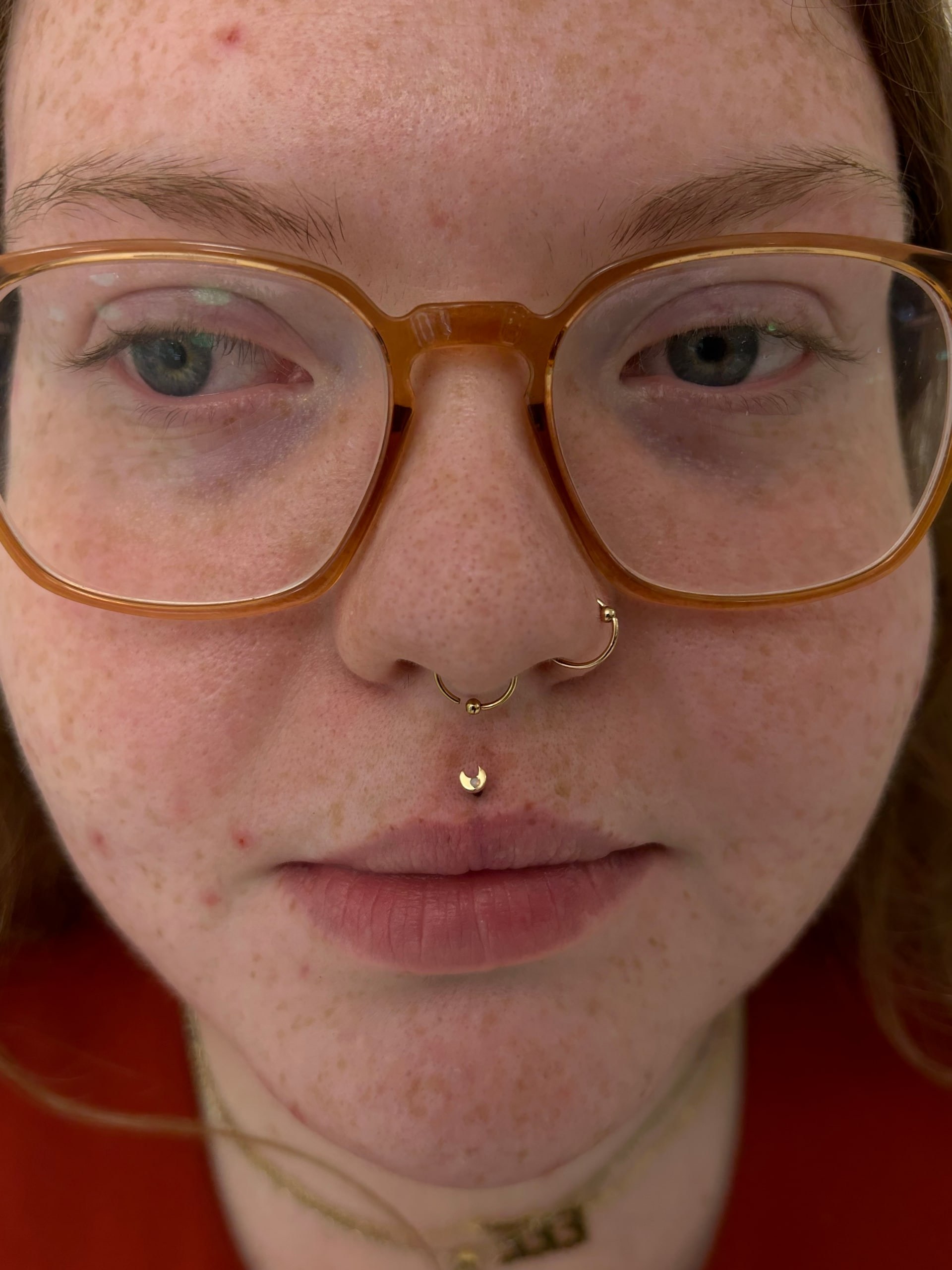 Labret piercing with tiny silver prong-set CZ stud below lower lip at Apollo LA