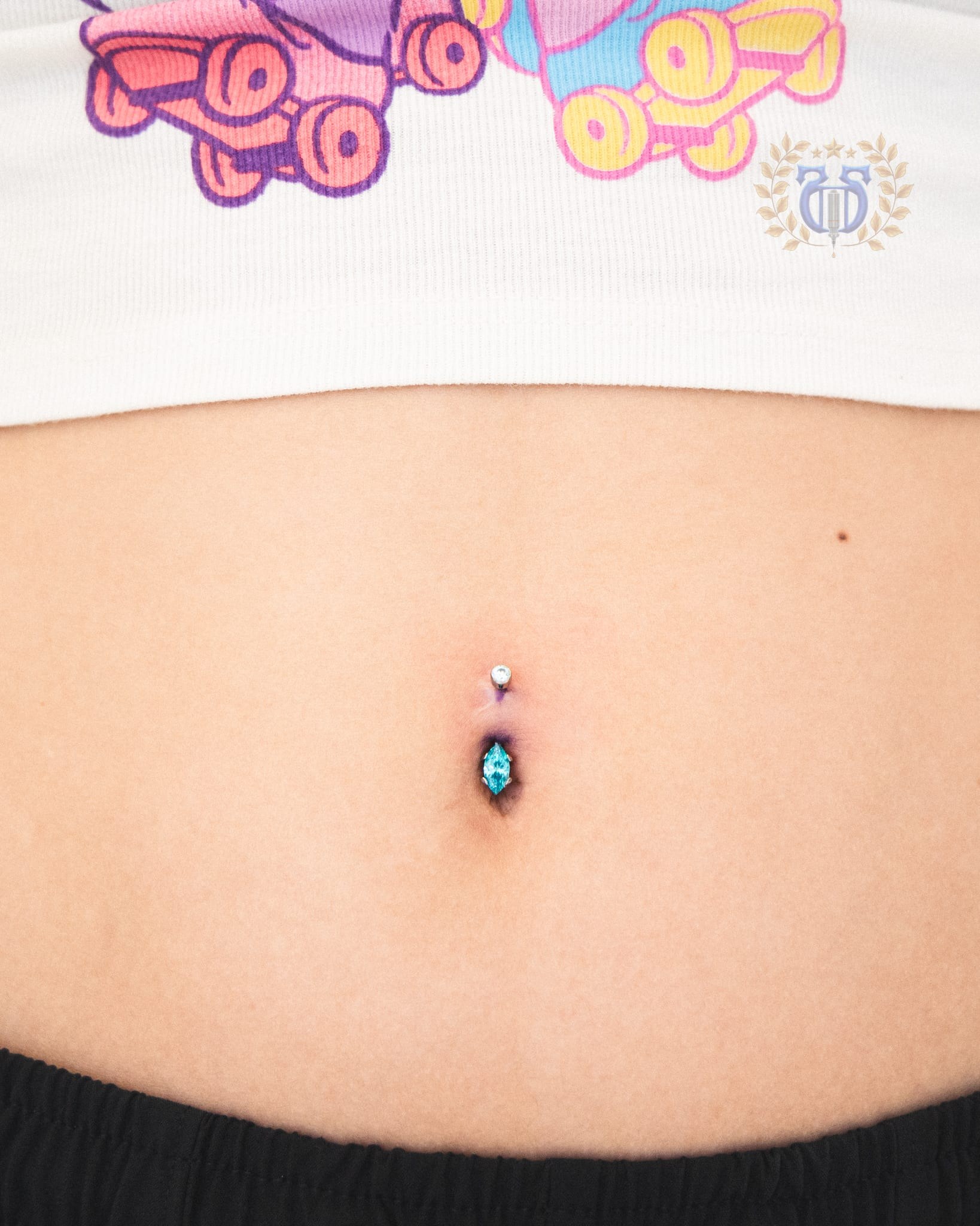 Navel piercing with marquise-cut aquamarine blue gemstone curved barbell at Apollo Studio